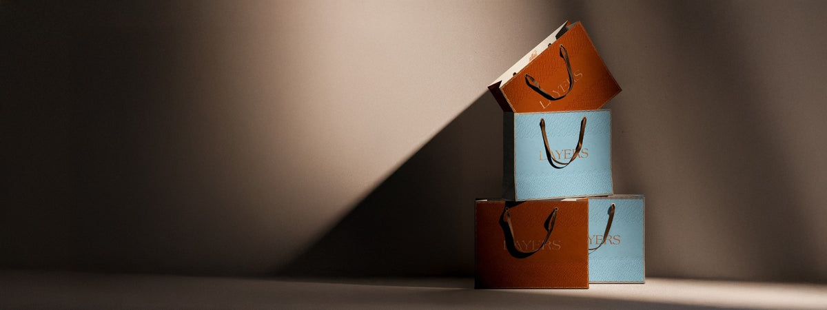 Stacked Layers gift bags in terracotta and light blue under dramatic side lighting